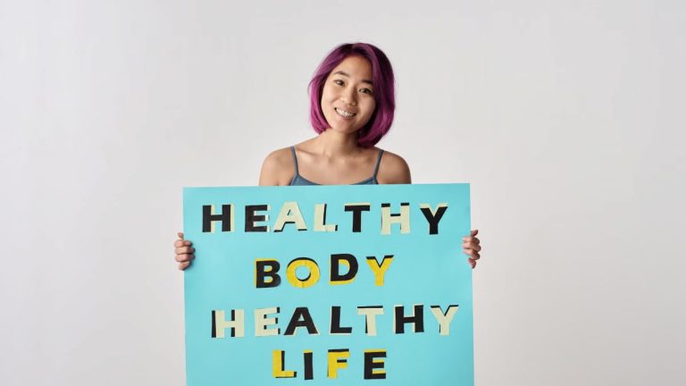 A young woman with purple hair holding a poster promoting a healthy lifestyle.