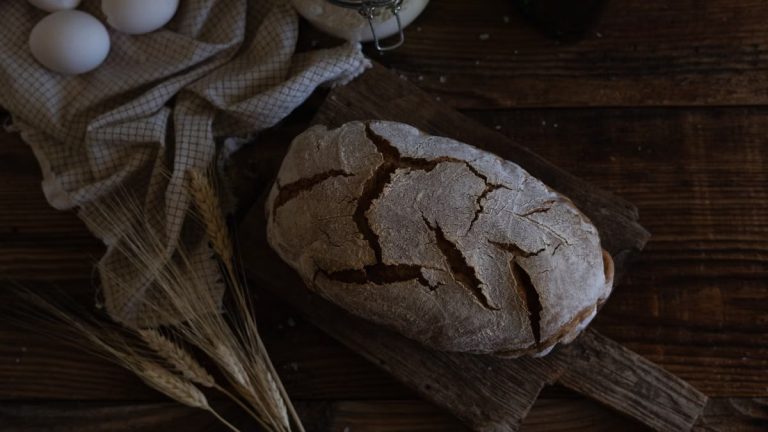 Artistic shot of homemade rustic bread with eggs and wheat on wooden table.